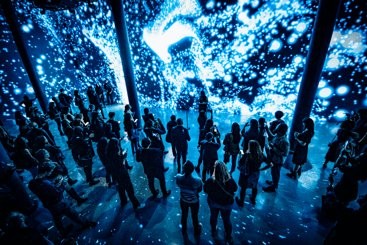 People stand in front of a wall of digital artwork