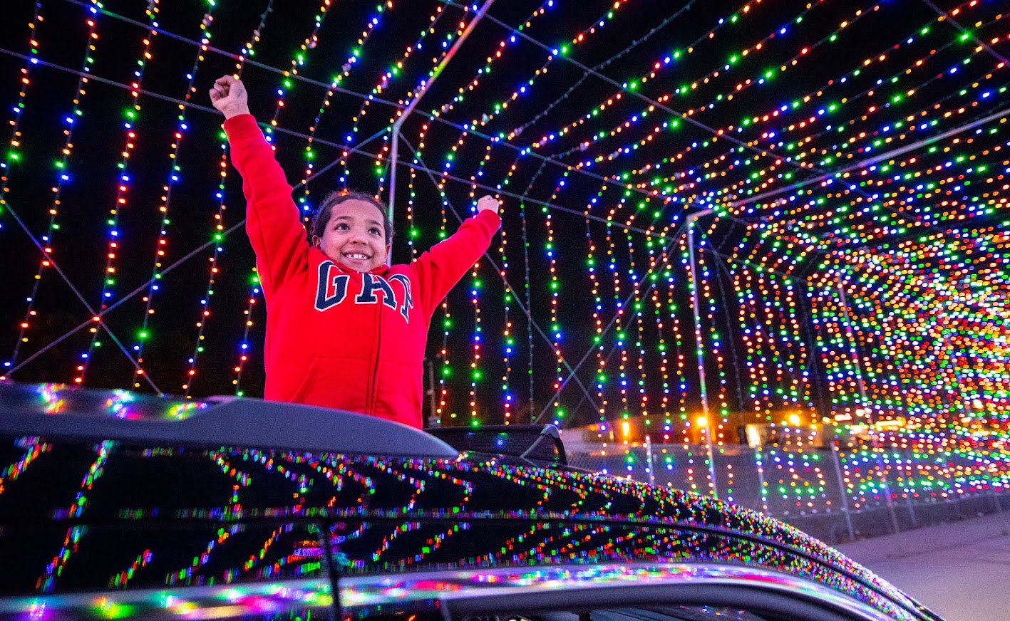 Child sticks out of car amid Christmas lights all around