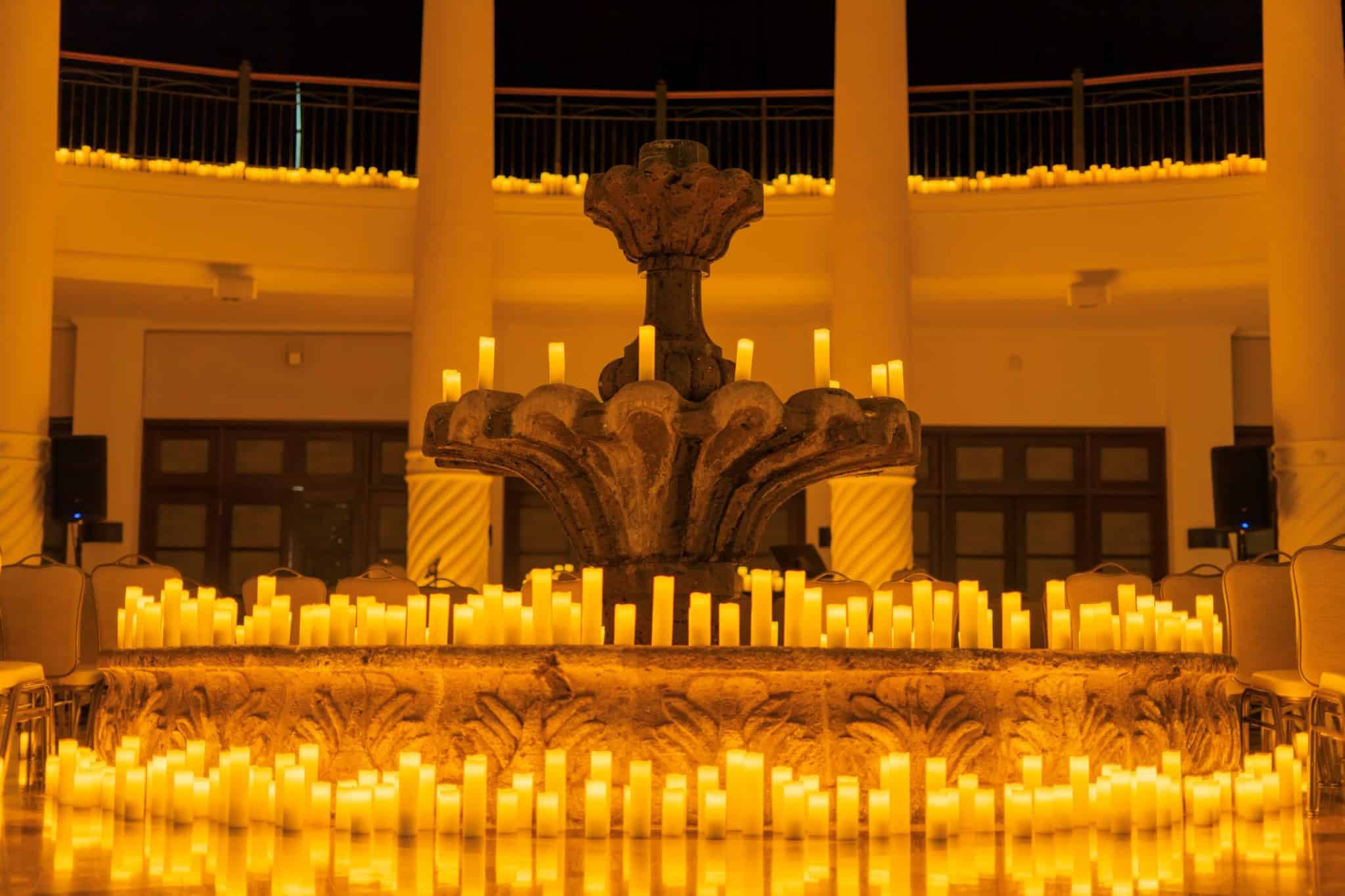 A stone fountain decorated with hundreds of candles.
