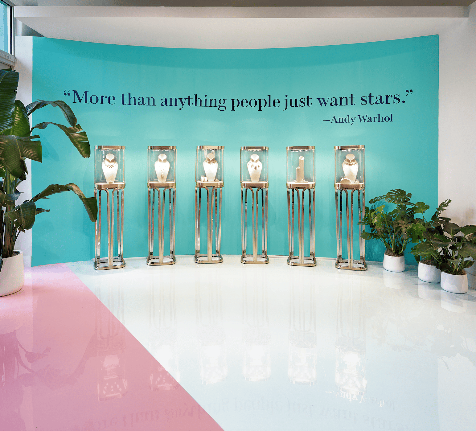 Andy Warhol quote on blue wall with jewelry stands behind glass
