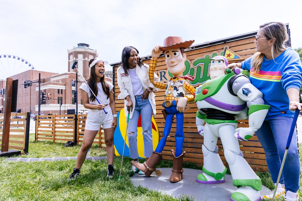 Minigolfers pose next to Buzz Lightyear and Woody for a photo