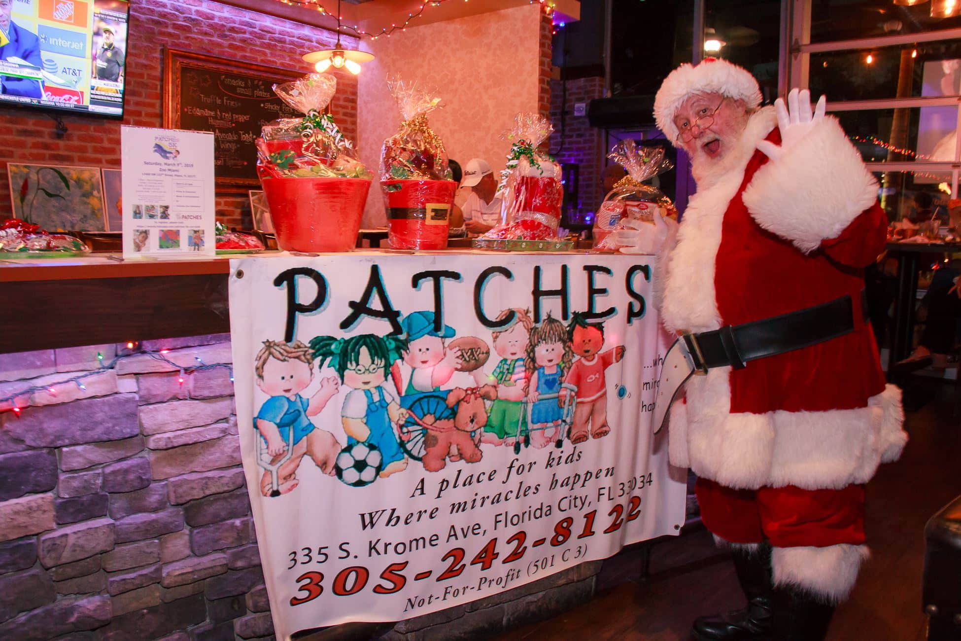 Santa stands in front of PATCHES sign for 'Shots for Tots'