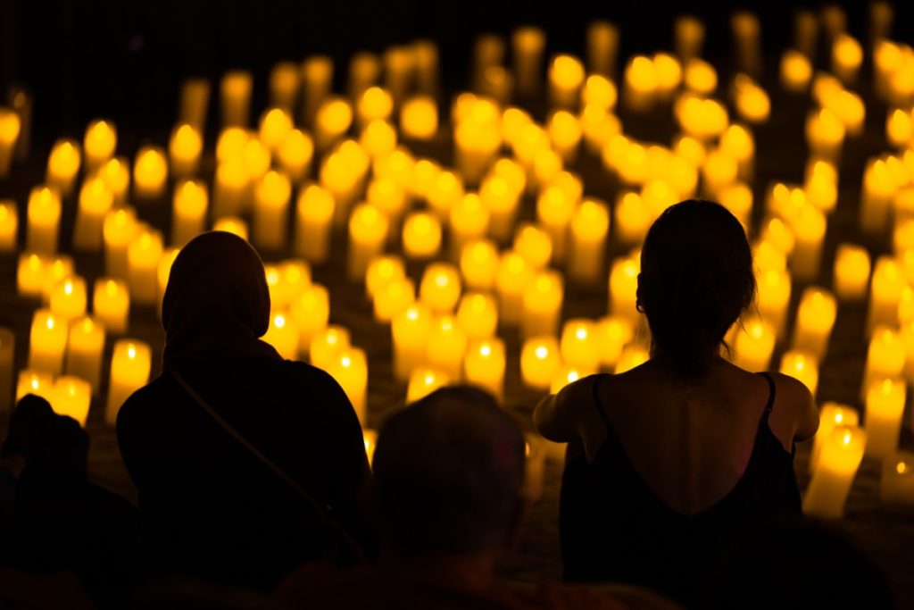 A silhouette of people facing hundreds of candles