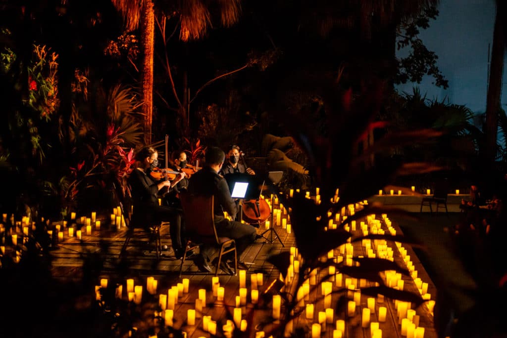 musicians on outdoor stage surrounded by candles for candlelight concert