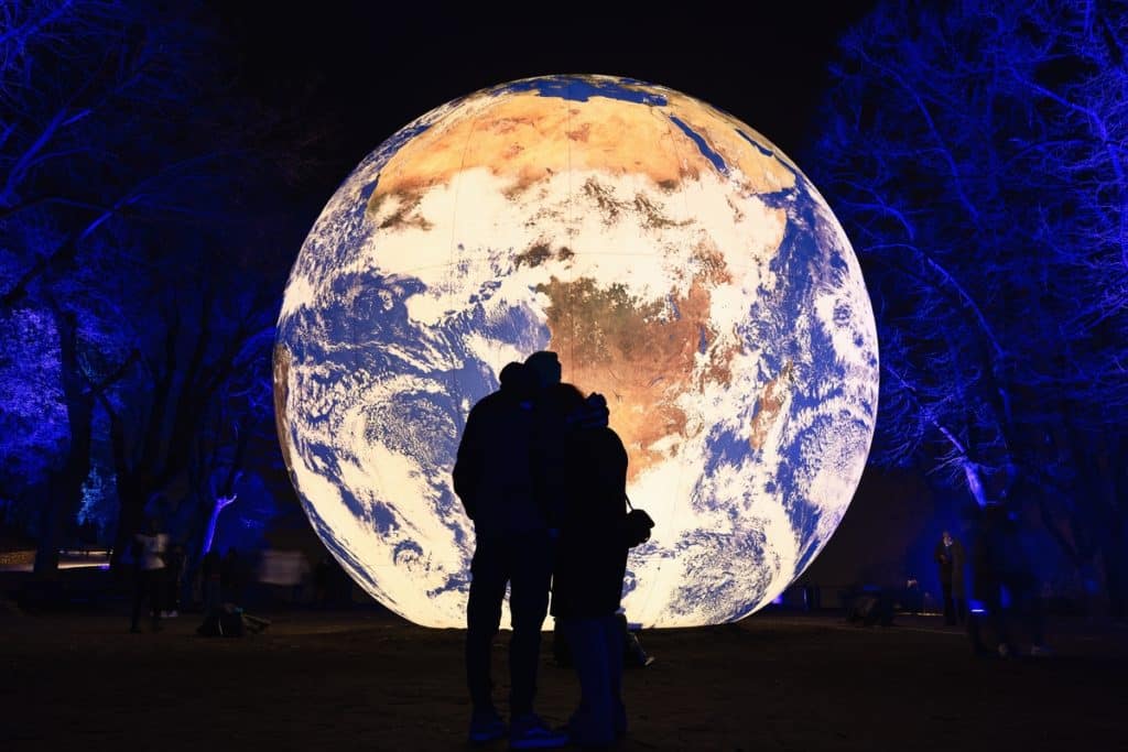 Brescia - Italia. February 15, 2023: Light is Life, (Festa delle Luci A2A), couple clinging to each other in the background of “Floating Earth” by Luke Jerram