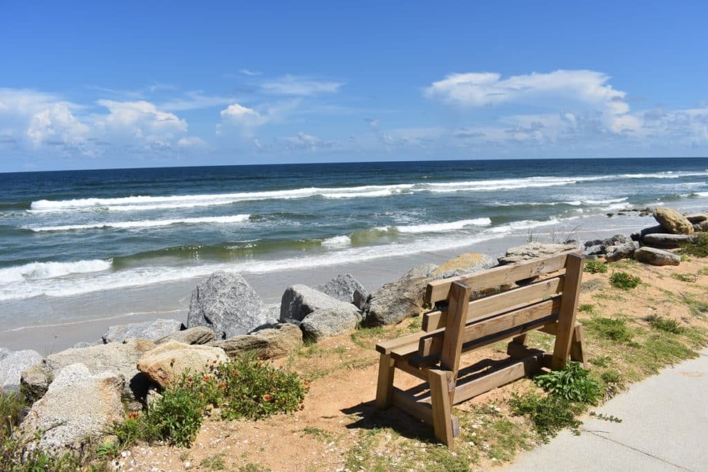 A daylight shot of a bench with an ocean view in Marineland Florida