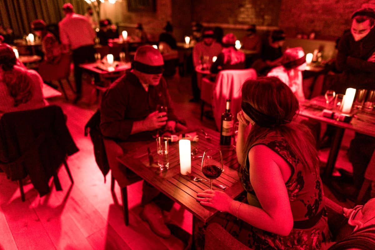 Couples sitting at tables during the Dining in the Dark experience.