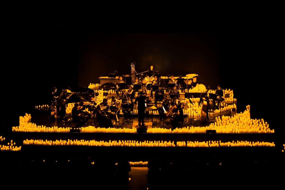 A Candlelight Orchestra performing on a stage in the glow of hundreds of flickering candles.