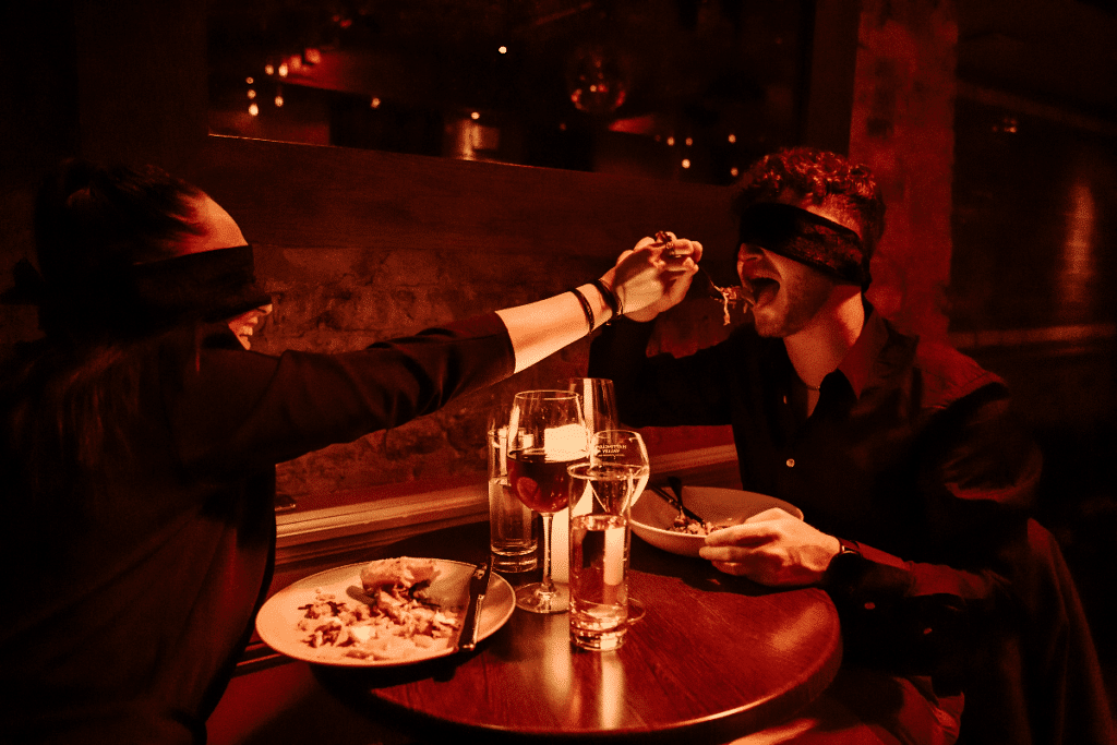 A couple feeding each other at the Dining in the Dark experience.