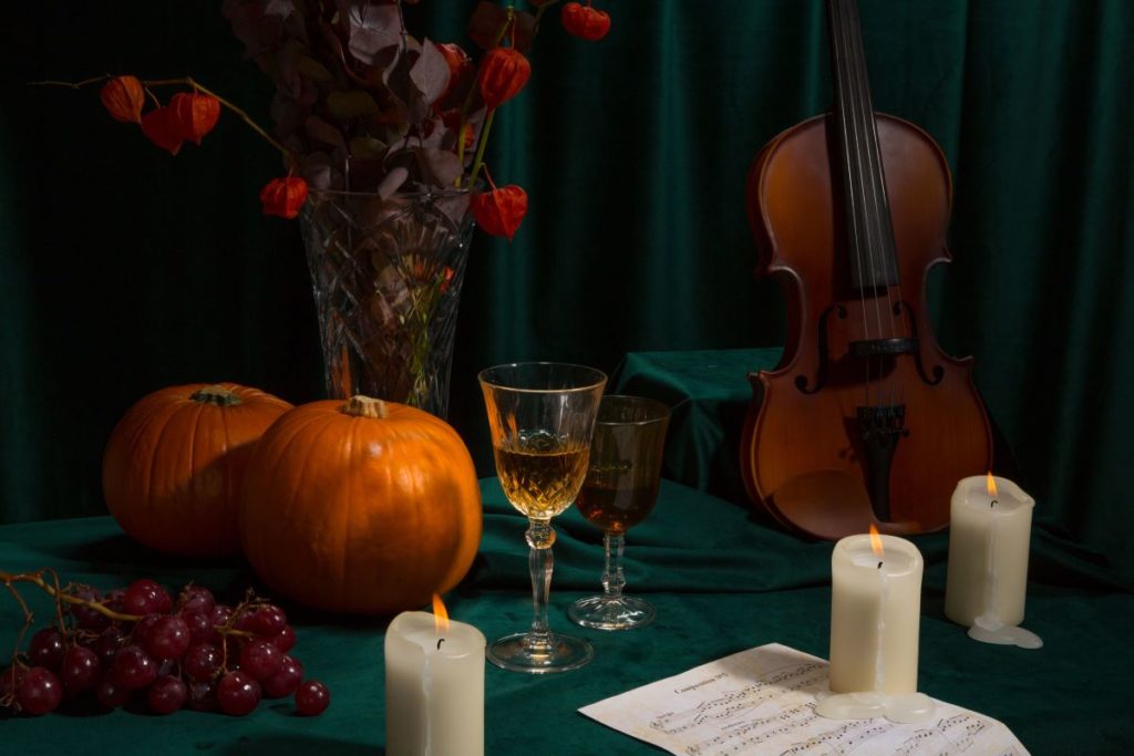 A pumpkin, candles, violin, and more on display promoting a Candlelight Halloween special.